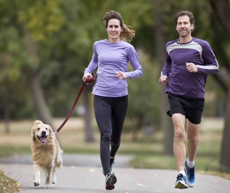 A couple running with a dog.