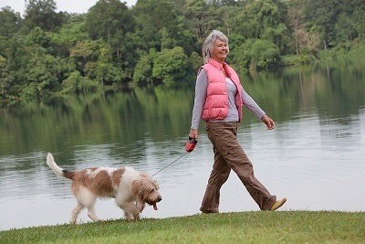 An old lady walking with a dog.